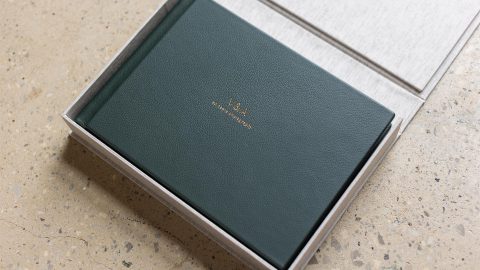 A green leather bound fine art wedding album in a fabric wrapped clamshell box