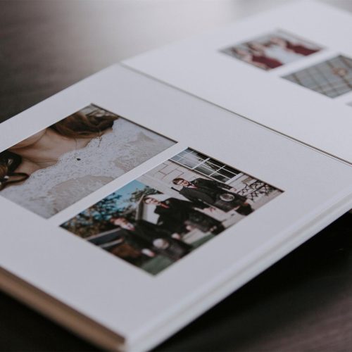 A matted album with wedding photos open on a table showing the bevel cut mounts with images underneath