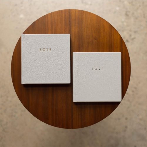 Two mini copy albums with leather covers and gold foiling on a round table