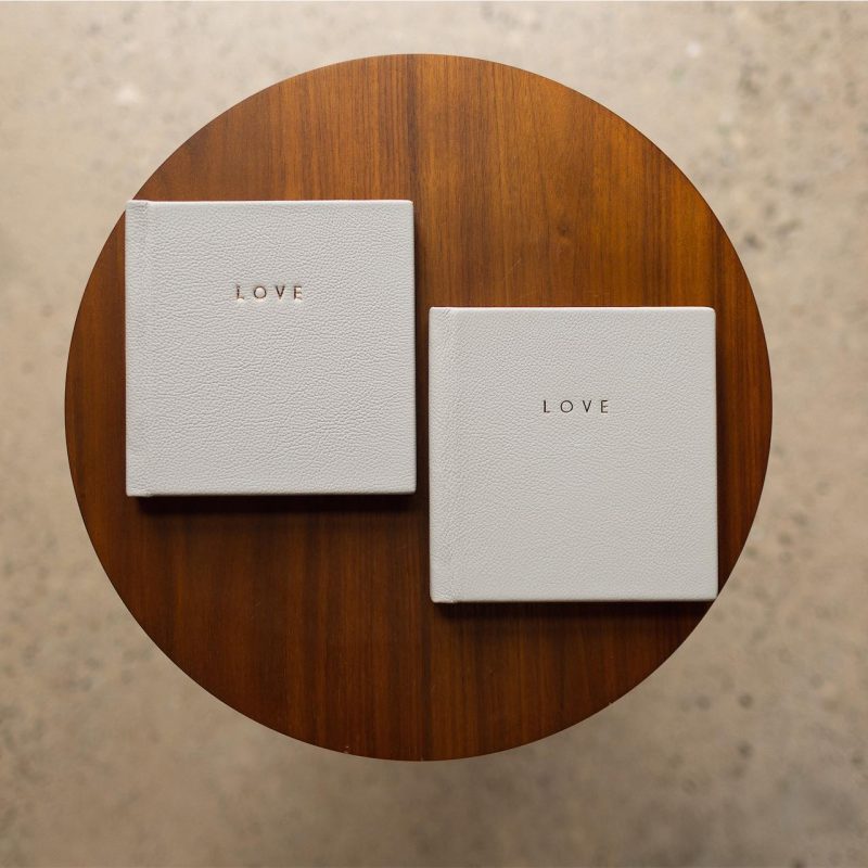 Two mini copy albums with leather covers and gold foiling on a round table
