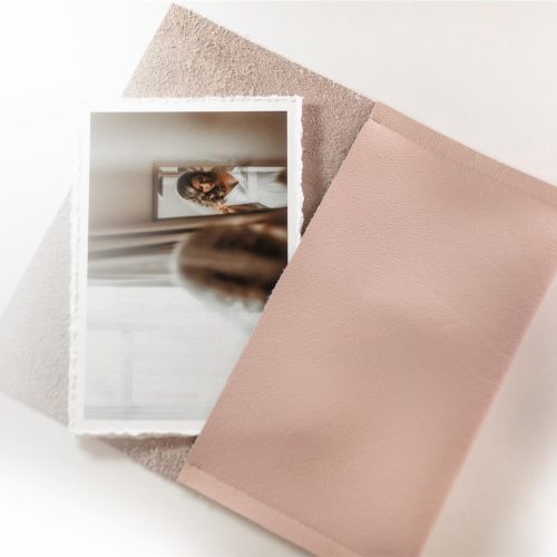 A pink leather wallet holding a collection of deckle edged archival quality fine art prints