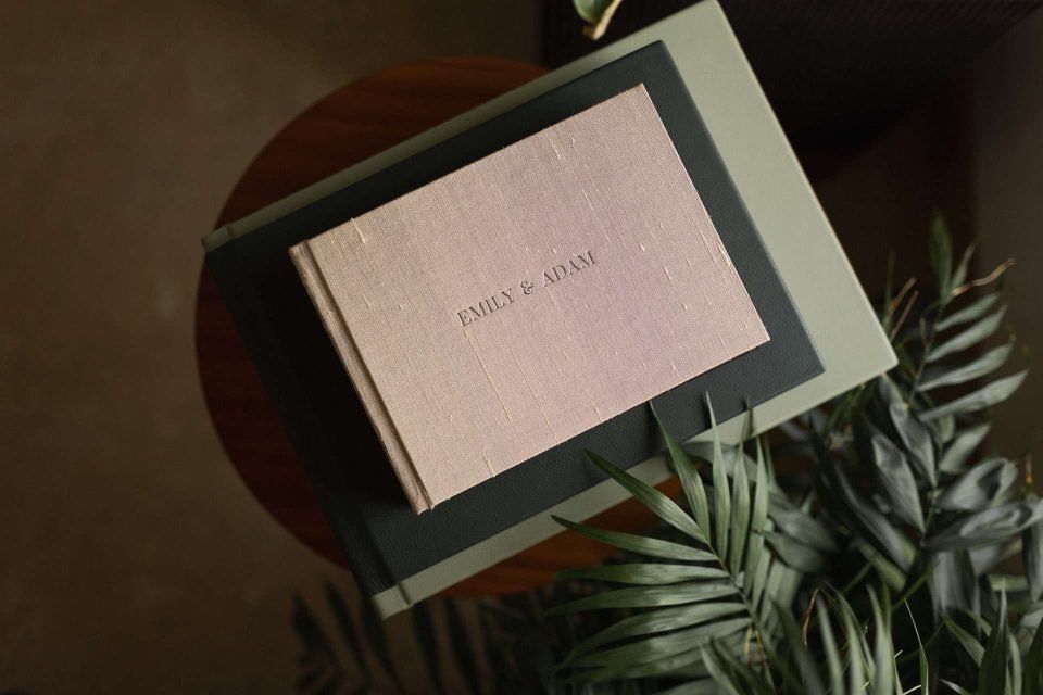 A silk covered album on top of several luxury UK supplier handmade photo albums