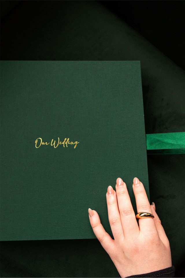 Green fabric covered clamshell box with woman's hand