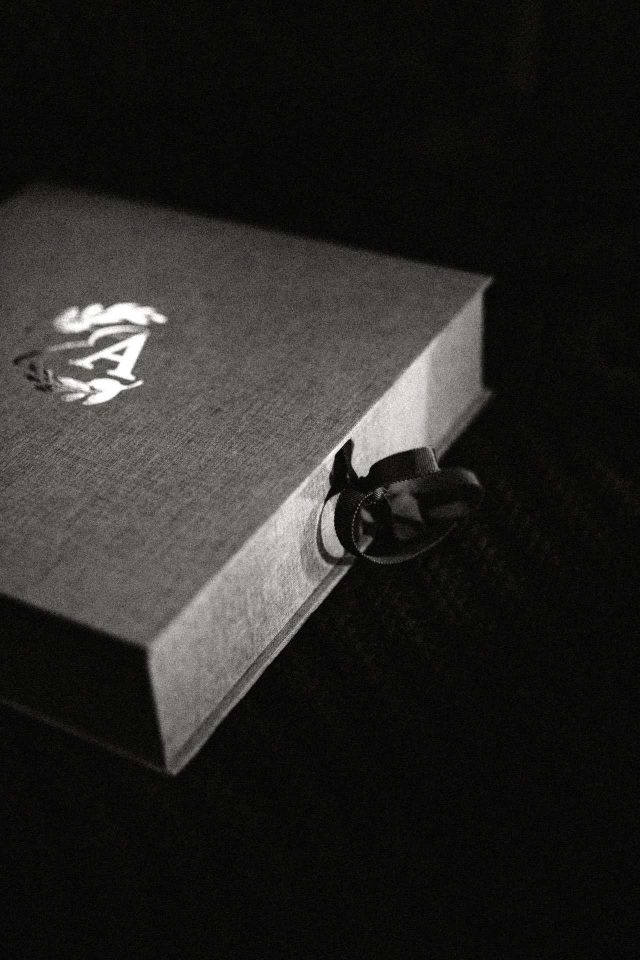 A dark and mood image of a clamshell box with gold foiled lid and a ribbon closure