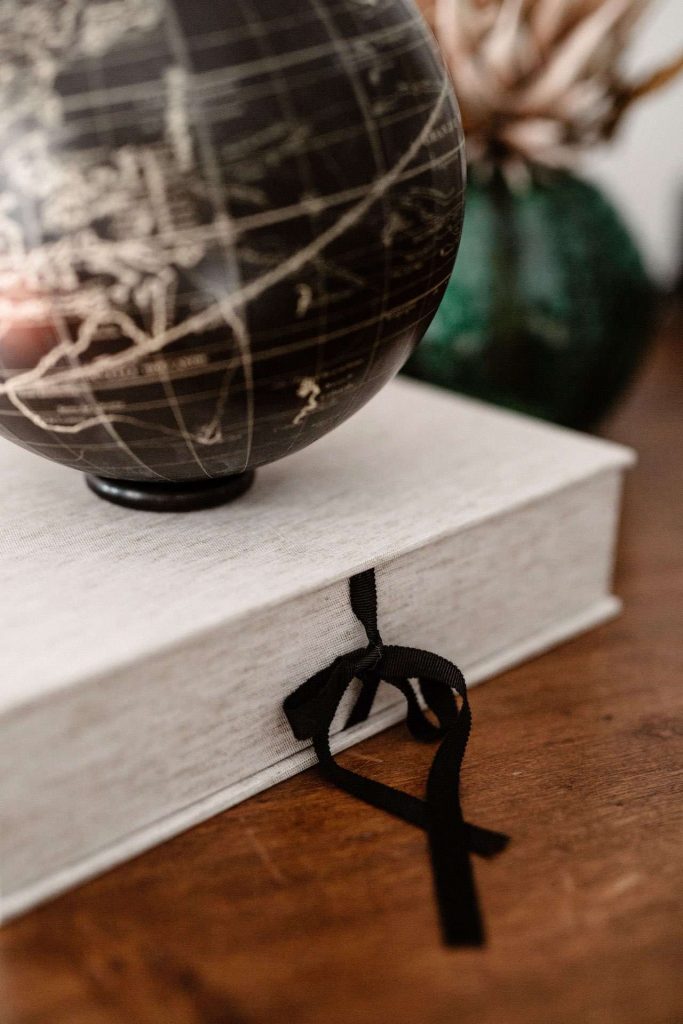A side shot of a fabric wrapped bespoke clamshell box with a black ribbon tied closure