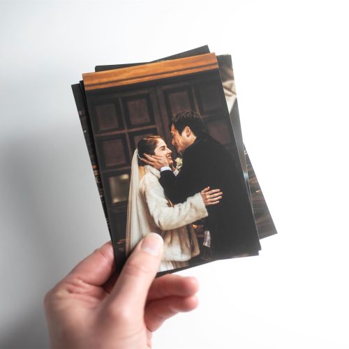 A hand holding several fine art prints of a wedding