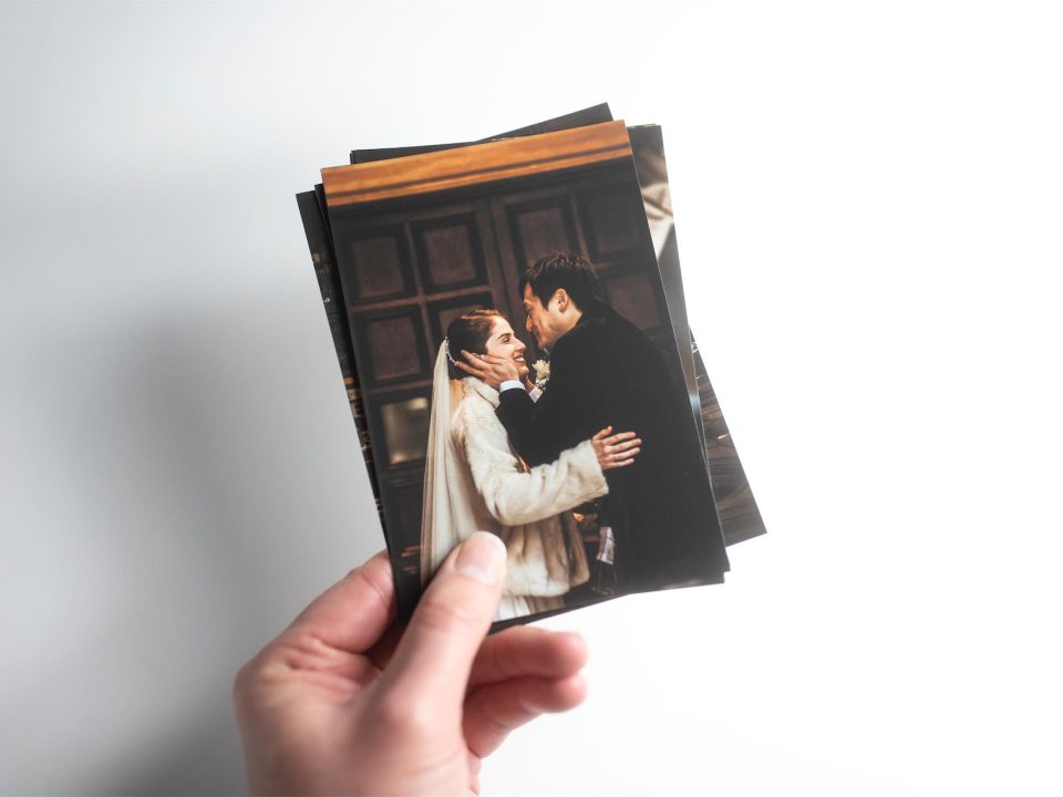 A hand holding several fine art prints of a wedding
