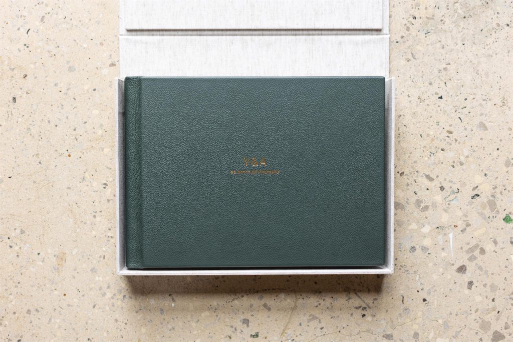 An opened landscape bespoke clamshell box with a green leather bound 14x10 album inside