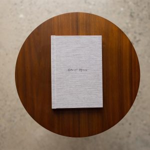 An A5 portrait mini album shot from above on a table with a parchment coloured fabric cover