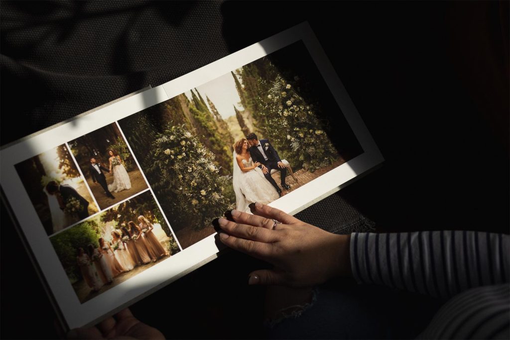 A low key image of a woman's hand about to turn the page of a photo album printed on fine art paper