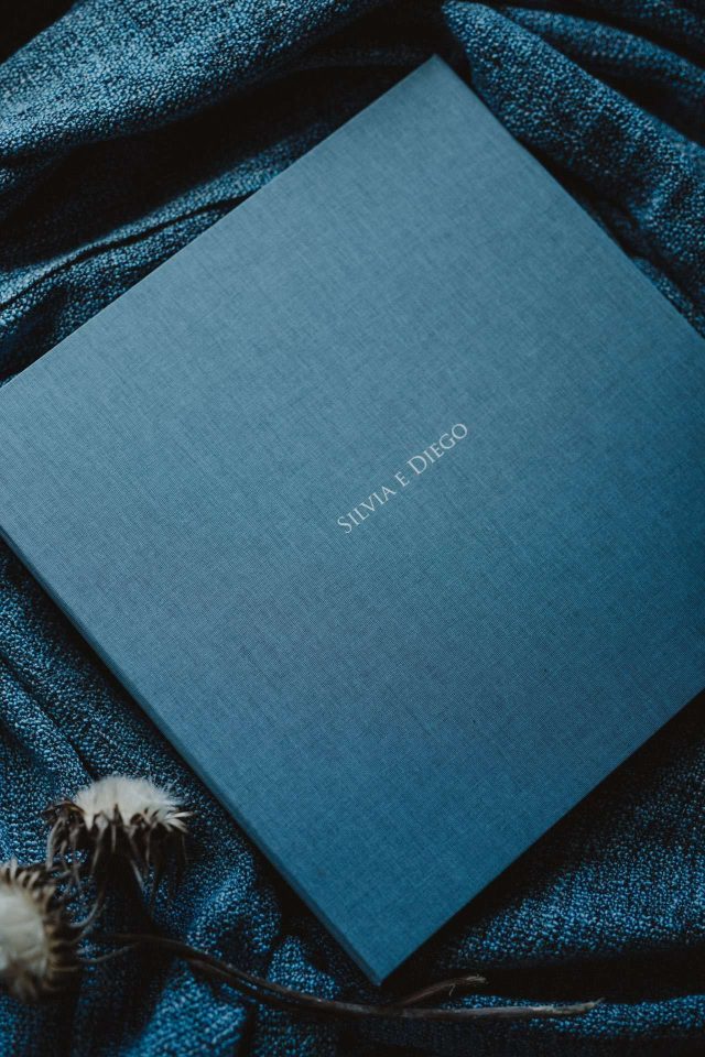 A blue fabric clamshell box with cover text printed in white ink