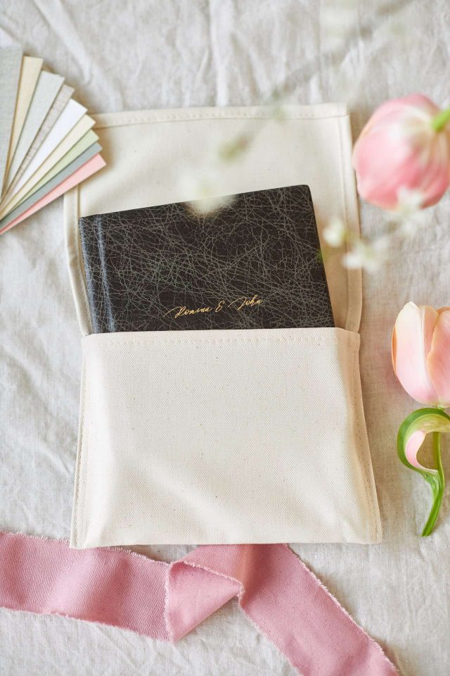 A vintage leather small wedding album in a natural cotton bag with flowers