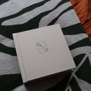 A 8x8 fabric cover matted photo album with front cover personalisation of a bespoke motif made of the highest quality materials