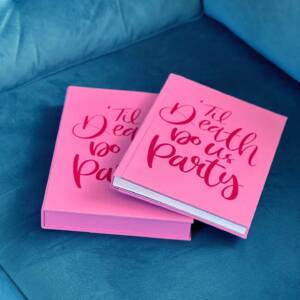 A bright pink coffee table style photo album on a blue sofa