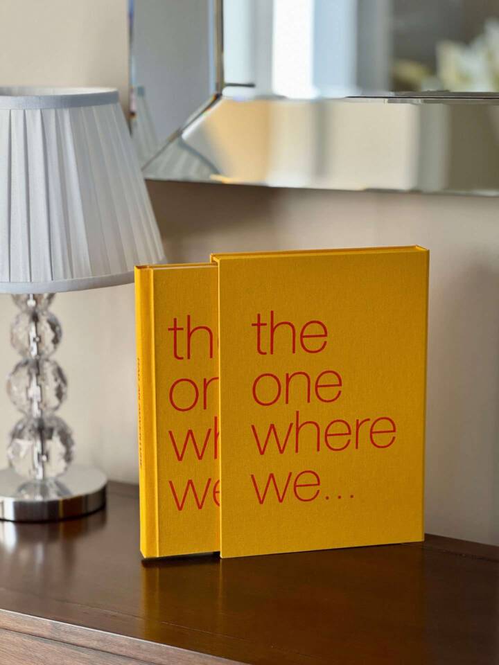 An orange-coloured coffee table book and slipcase on a sideboard with the book partly removed from the slipcase