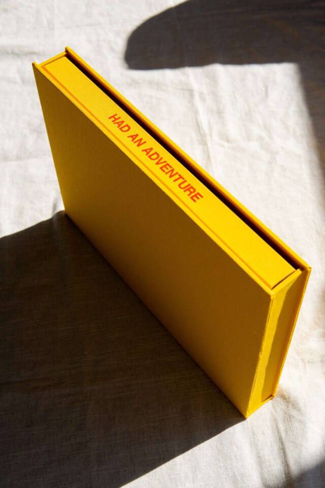 An orange or mango coloured coffee table book with spine text reading Had An Adventure