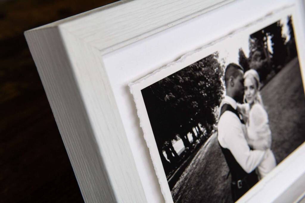 A close-up detail shot of a deckle-edge fine art print that has been float-mounted in a frame showing off the soft ripped edges of the print and the white moulding of the frame