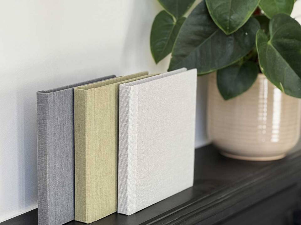 Three wedding album copies in a row on a table each with fabric covers