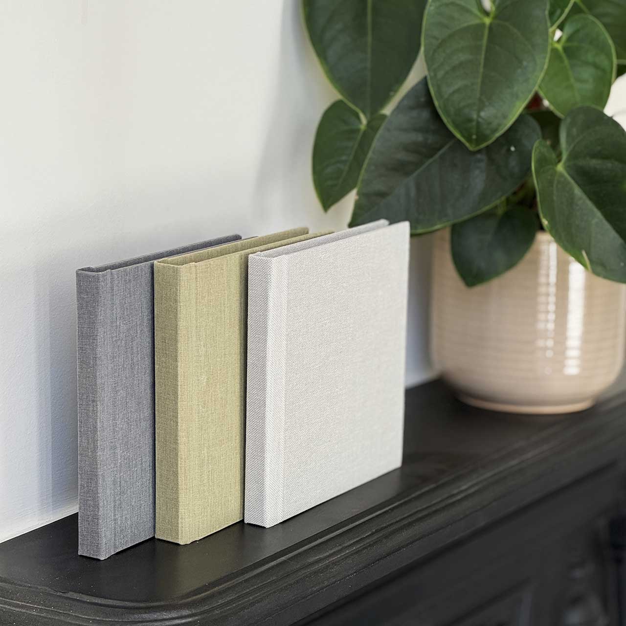 Three wedding album copies in a row on a table each with fabric covers